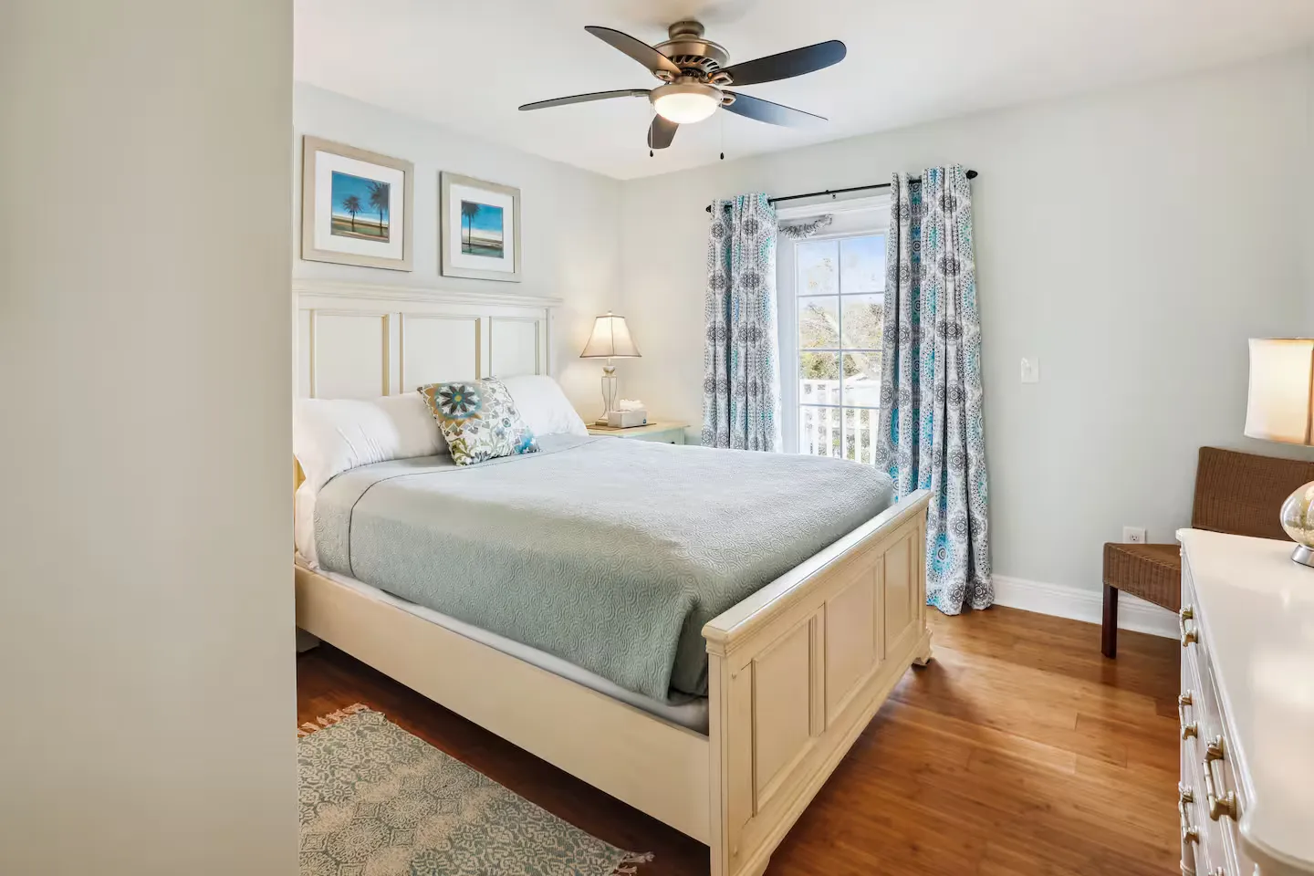 Bedroom with a white wooden bed, ceiling fan, hardwood floors, and a glass door leading to a balcony.