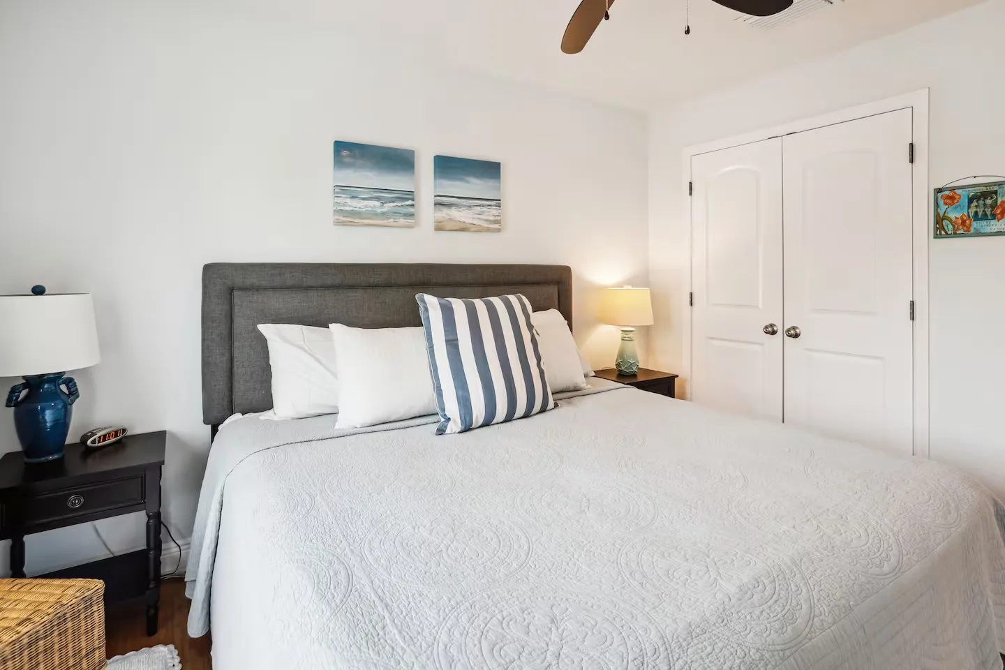 Bedroom with a bed featuring a gray upholstered headboard, nightstands with lamps, and a white double-door closet.