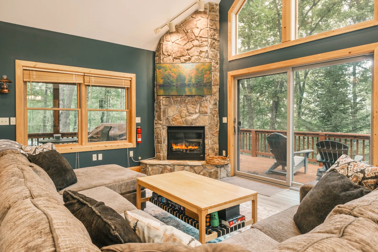 Living room with a stone corner fireplace, large sectional sofa, coffee table, and sliding glass doors leading to an outdoor deck.