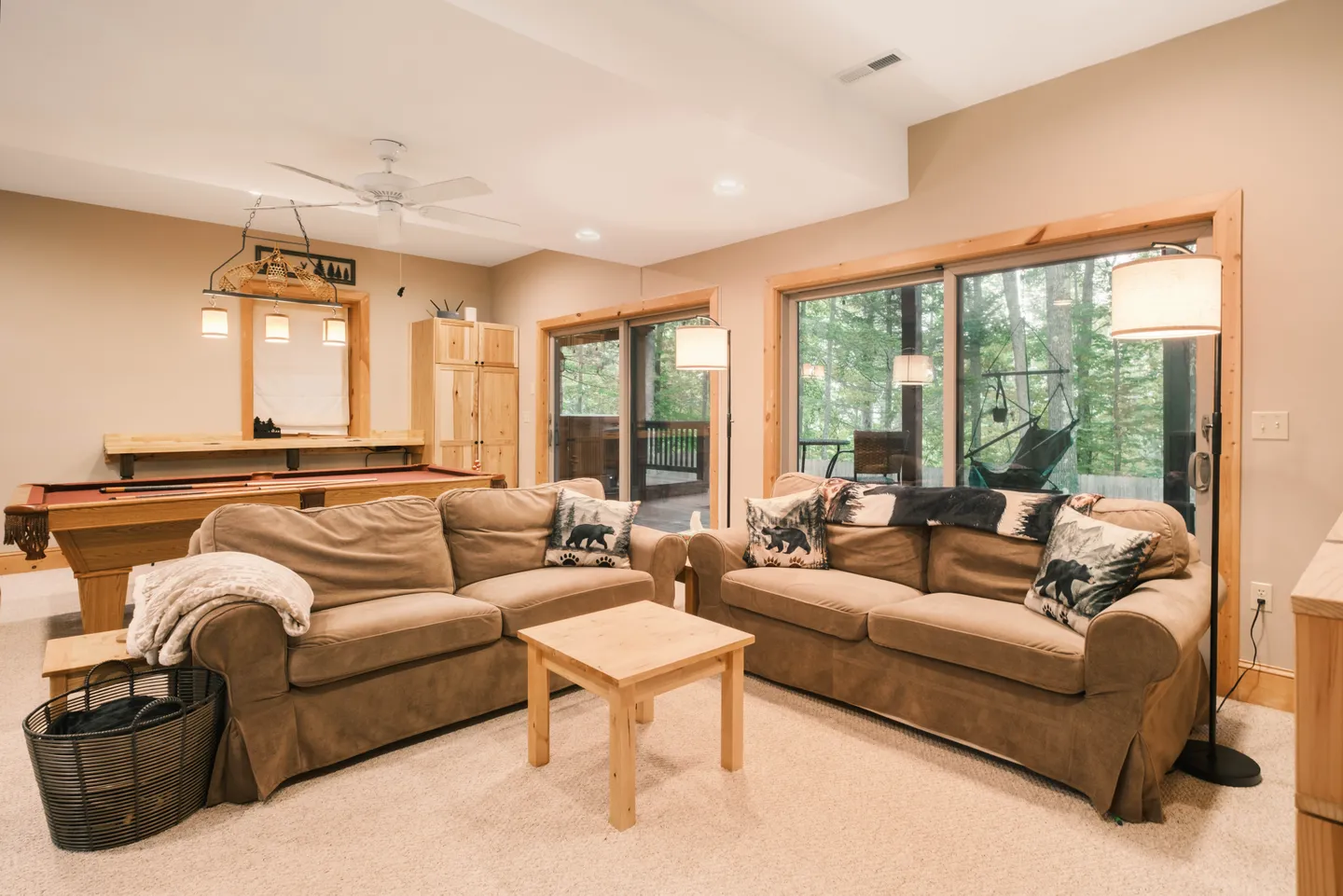 Game room and lounge area with two brown couches, a pool table, and sliding glass doors leading outside.