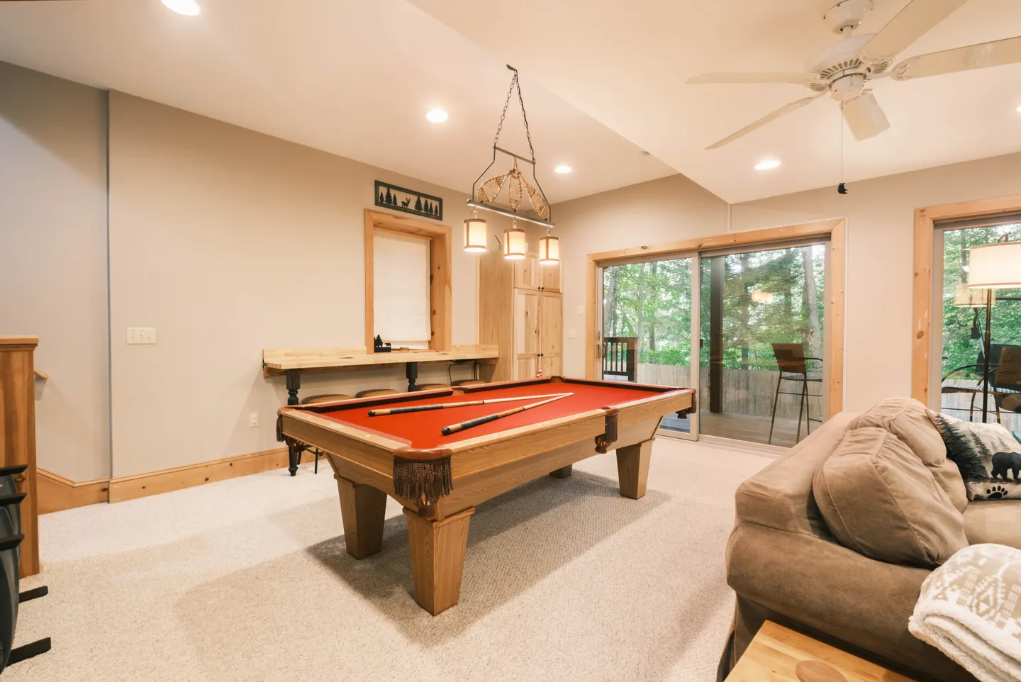 Game room featuring a red felt pool table, carpeted flooring, and sliding glass doors leading to an outdoor deck.