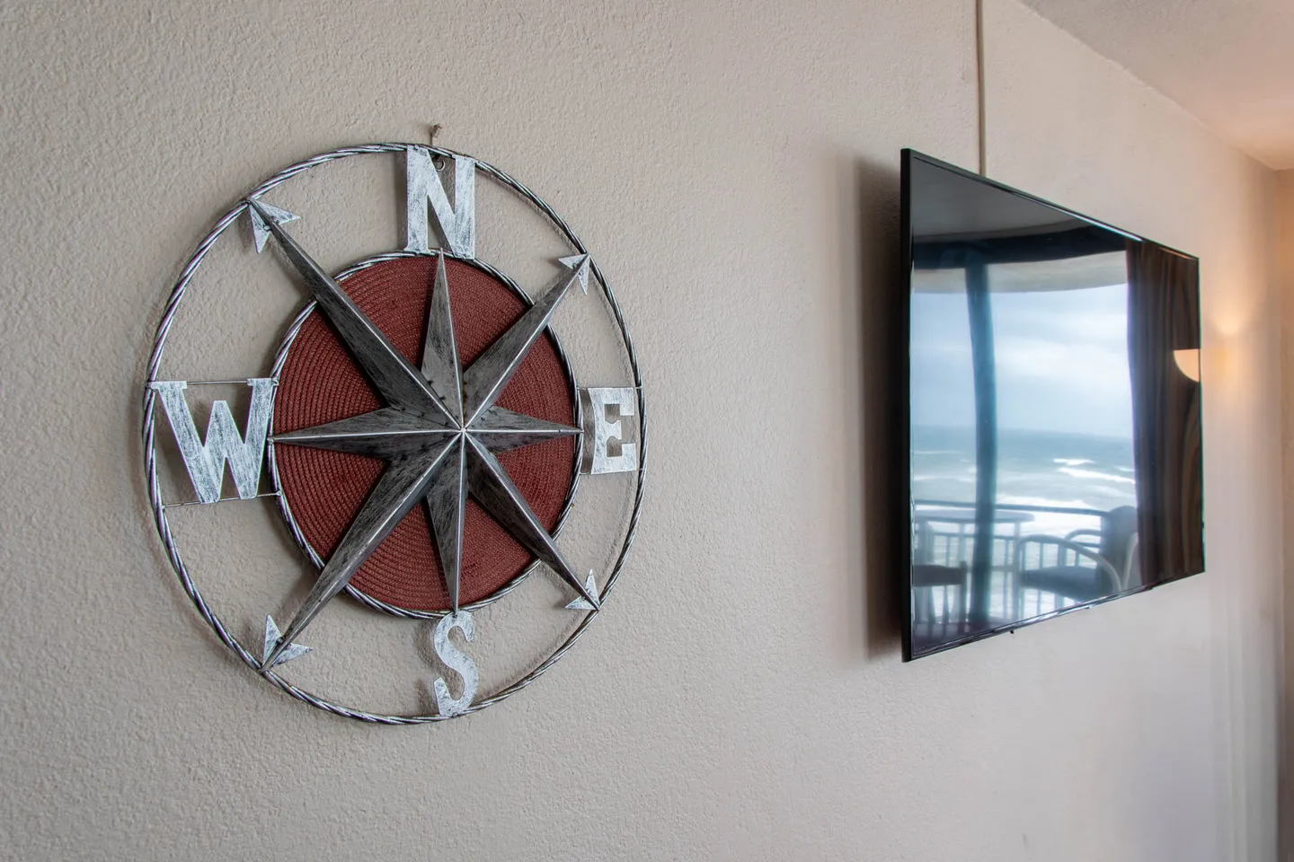 A close-up view of a metal compass rose wall decoration beside a wall-mounted flat-screen TV.
