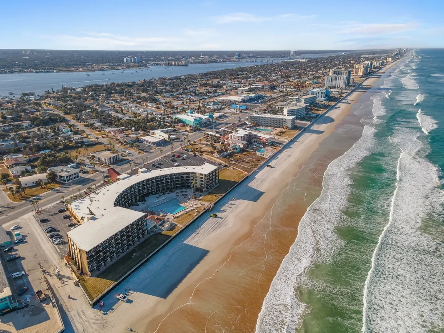 Aerial view of a beachfront condominium complex next to the ocean and sandy coastline.