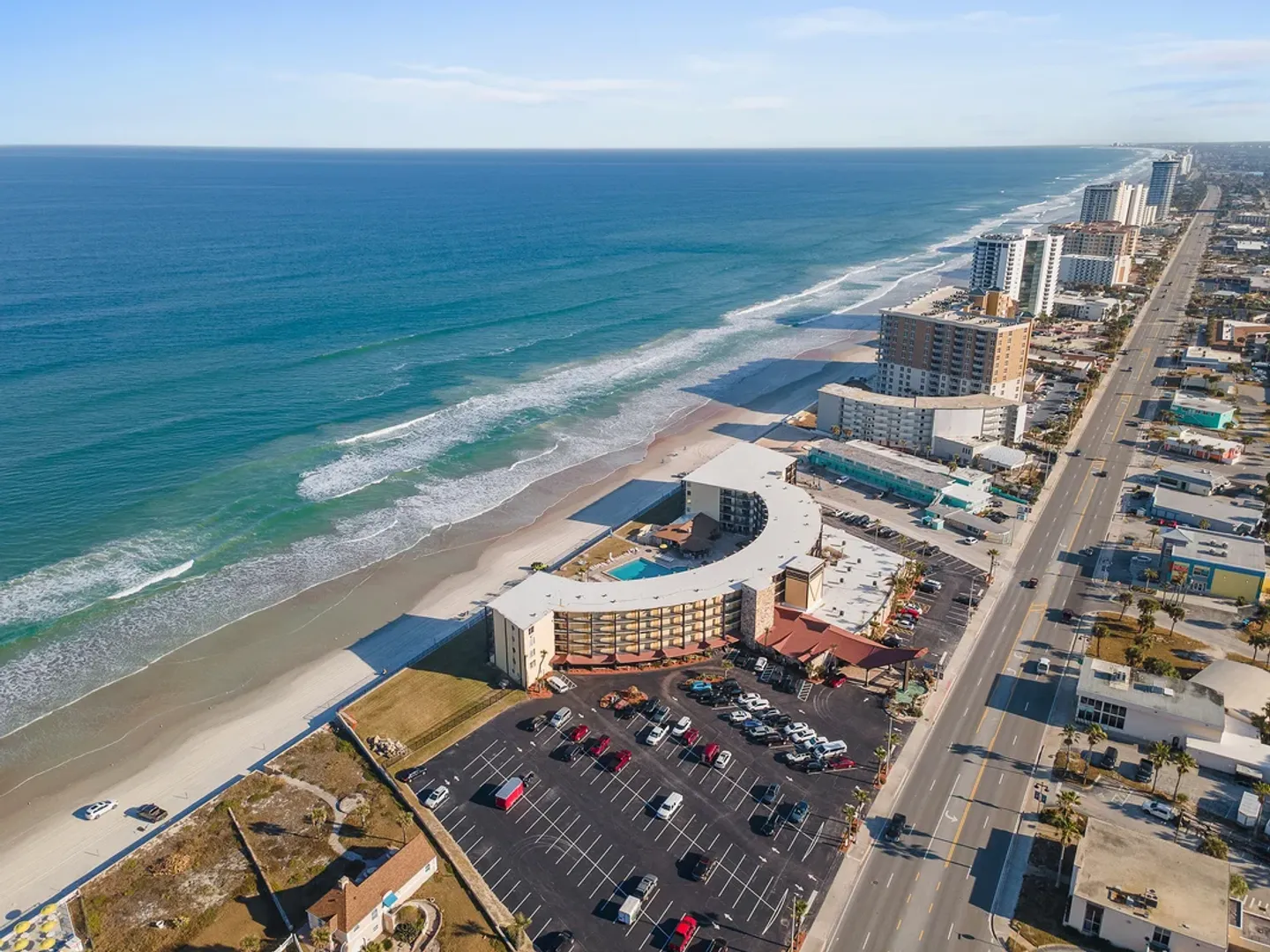 Aerial view of an oceanfront resort building along a sandy beach and coastline.