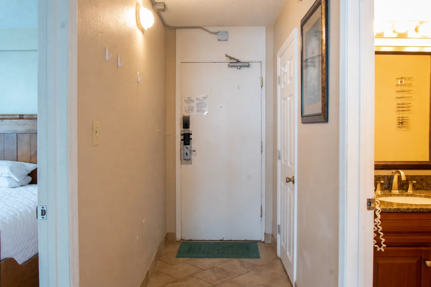 Entry hallway with tiled flooring, a white front door, and doorways leading to a bedroom and bathroom.
