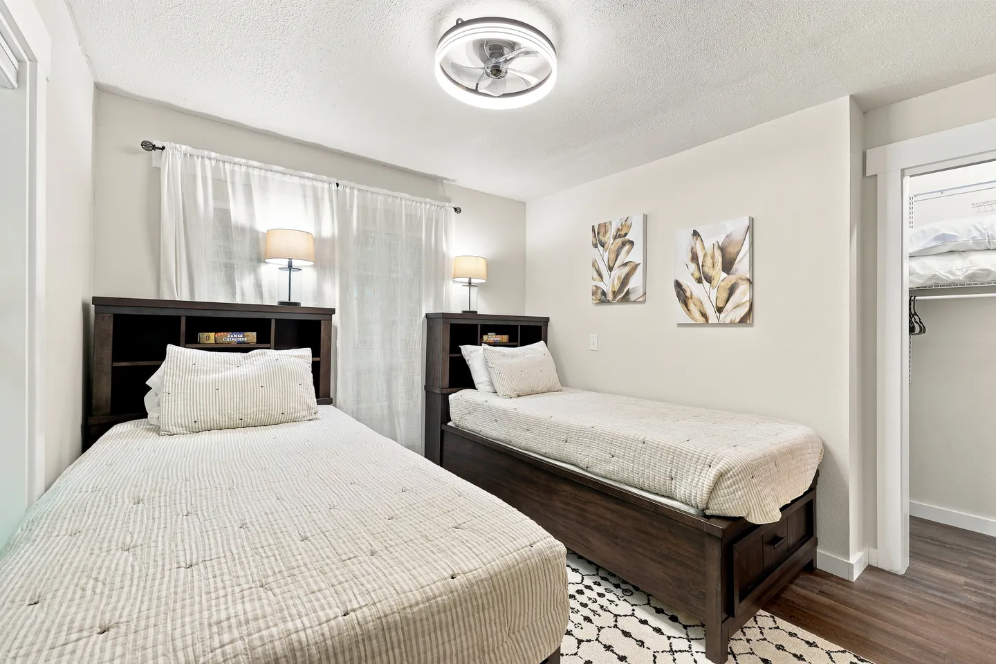 Bedroom with two twin beds featuring dark wood bookcase headboards, matching quilted bedding, and a ceiling fan light.