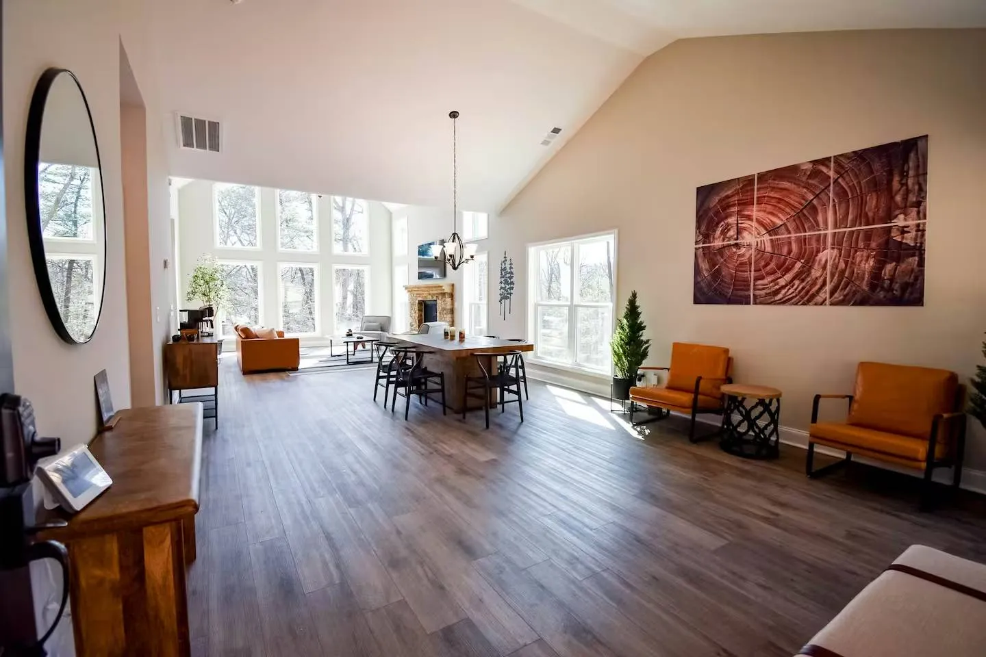Open-concept great room with vaulted ceilings, dining table, seating, and wall of windows.