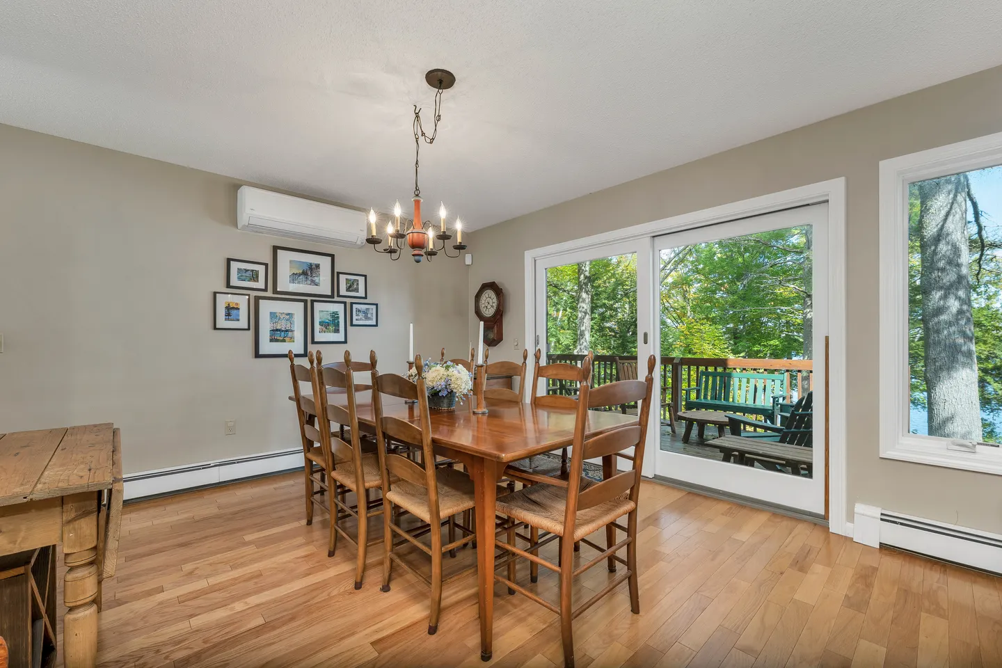 Dining room with wooden table and chairs, chandelier, sliding glass doors to a deck, and light wood flooring.