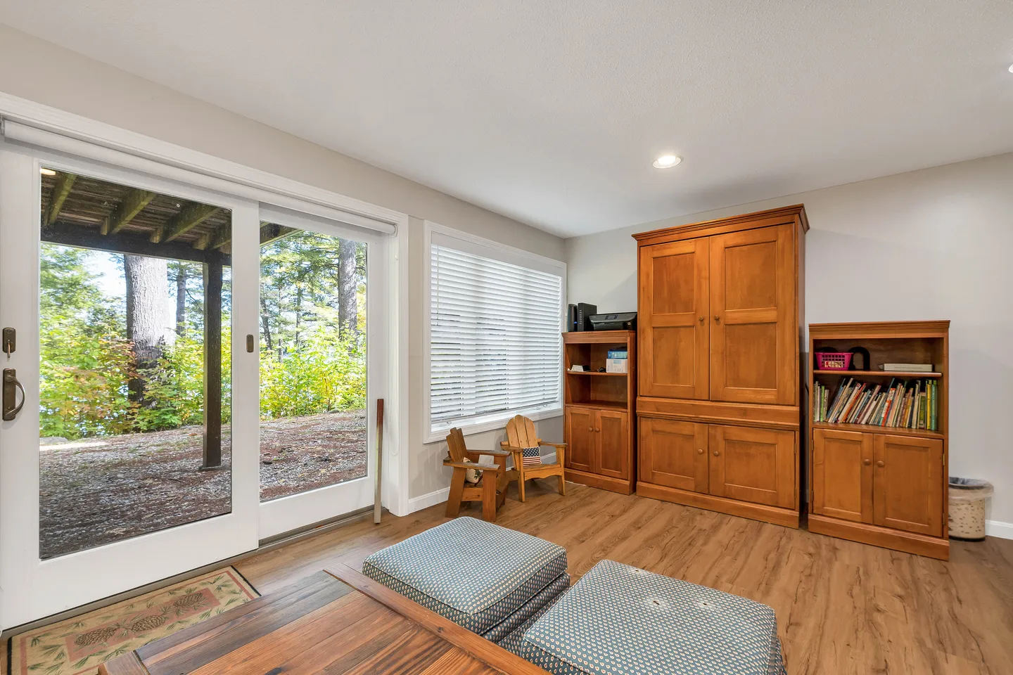Living area with sliding glass doors opening to an outdoor patio and wooden cabinetry against the wall.