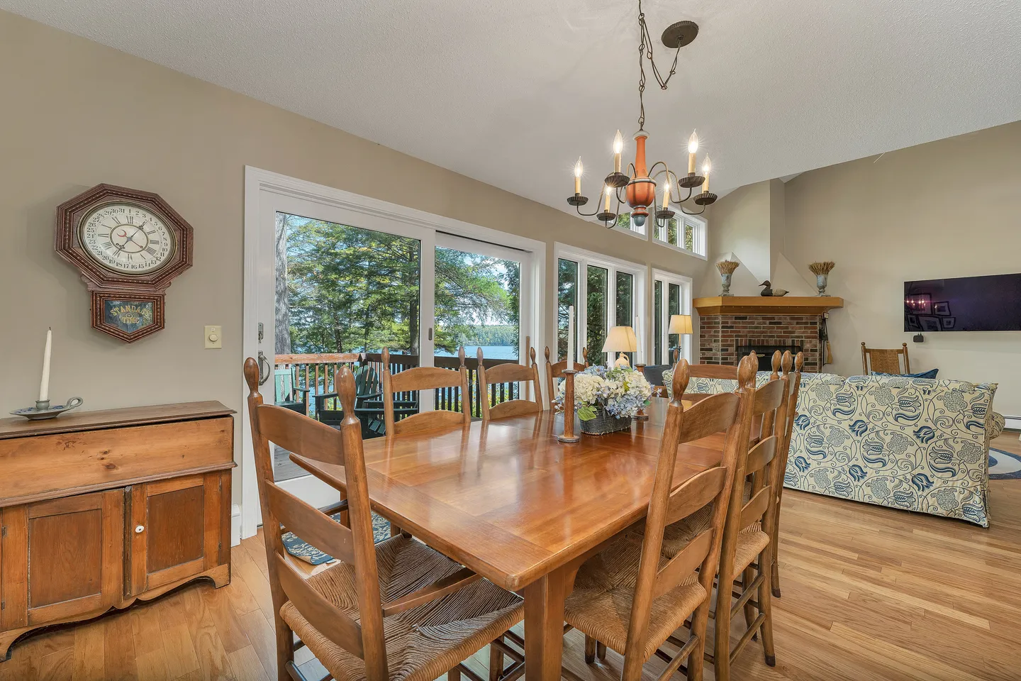 Dining area with a wooden table, woven chairs, and a chandelier, adjacent to sliding glass doors that lead to an outdoor deck.