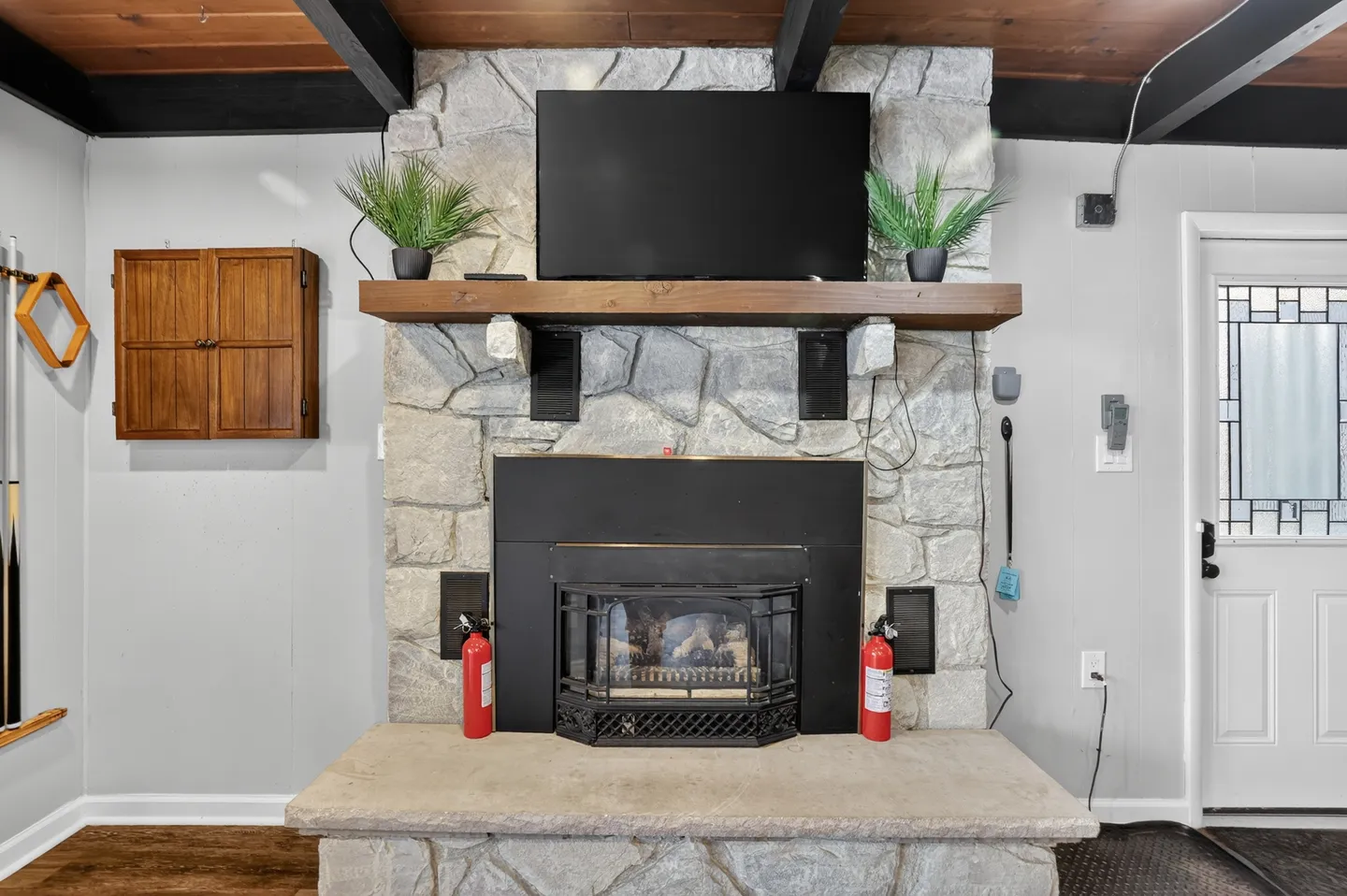 A stone fireplace with a raised hearth, wood mantel, and a flat-screen television mounted above.