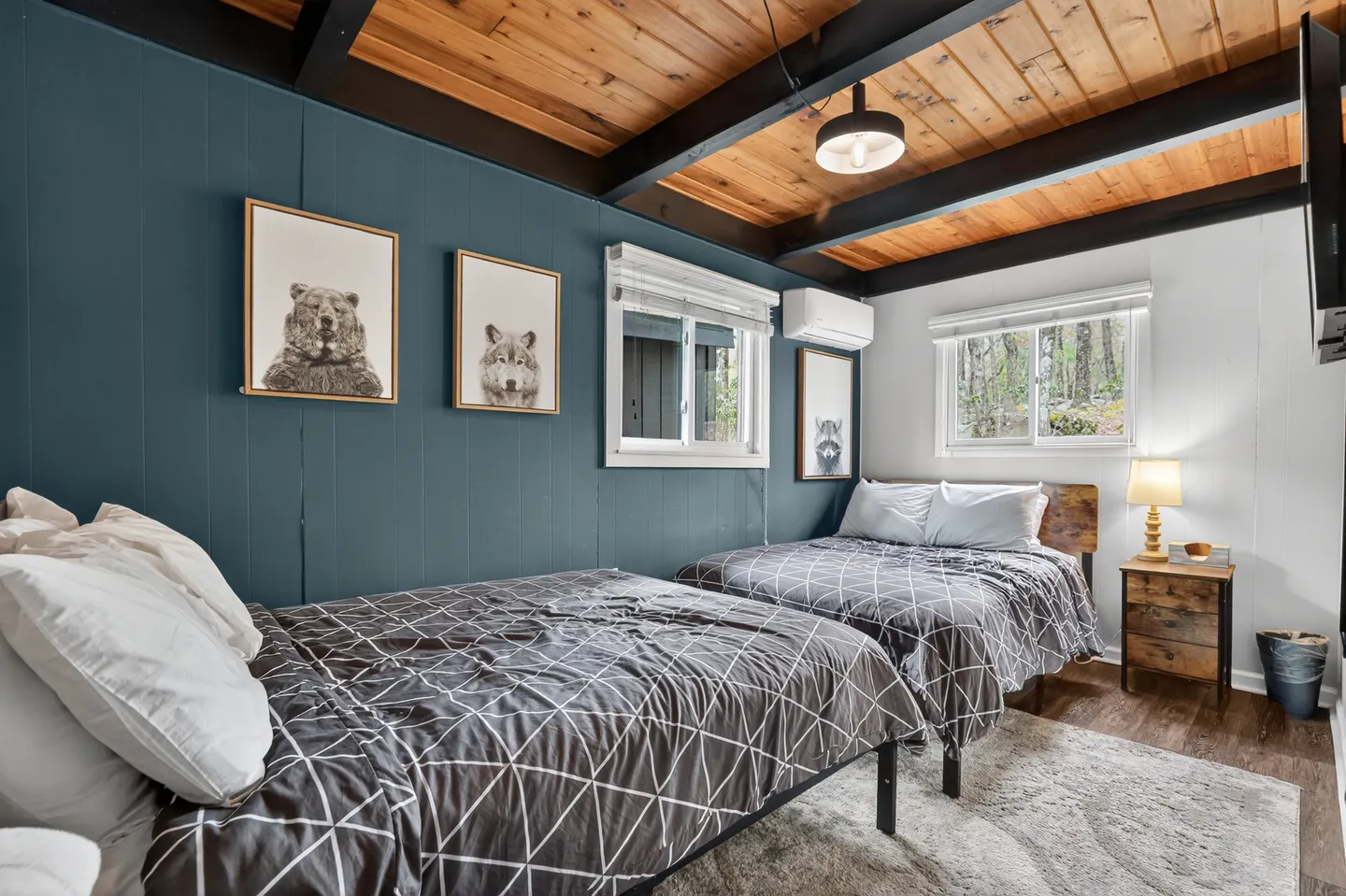 Bedroom with two beds, blue paneled accent wall, and exposed wood beam ceiling