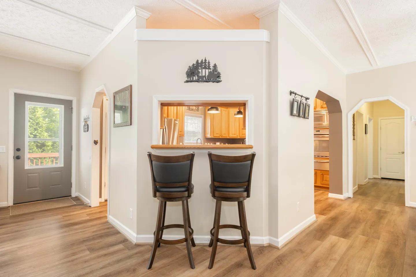 Pass-through breakfast bar with two wooden barstools looking into the kitchen.