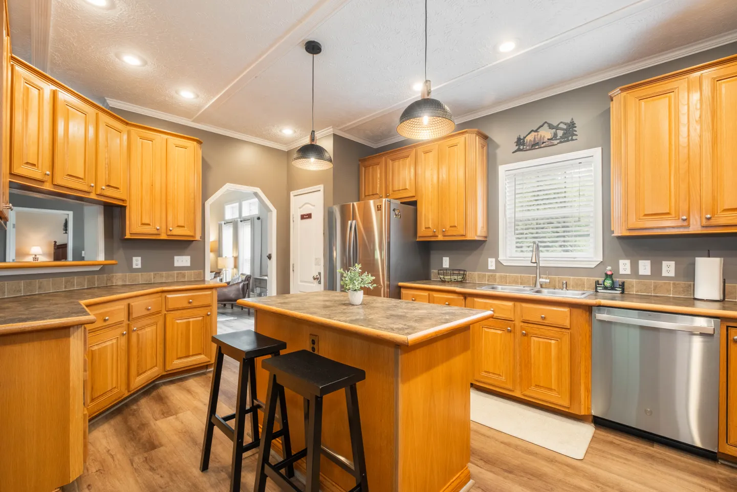 Kitchen featuring light wood cabinets, dark countertops, a center island with barstools, and stainless steel appliances.