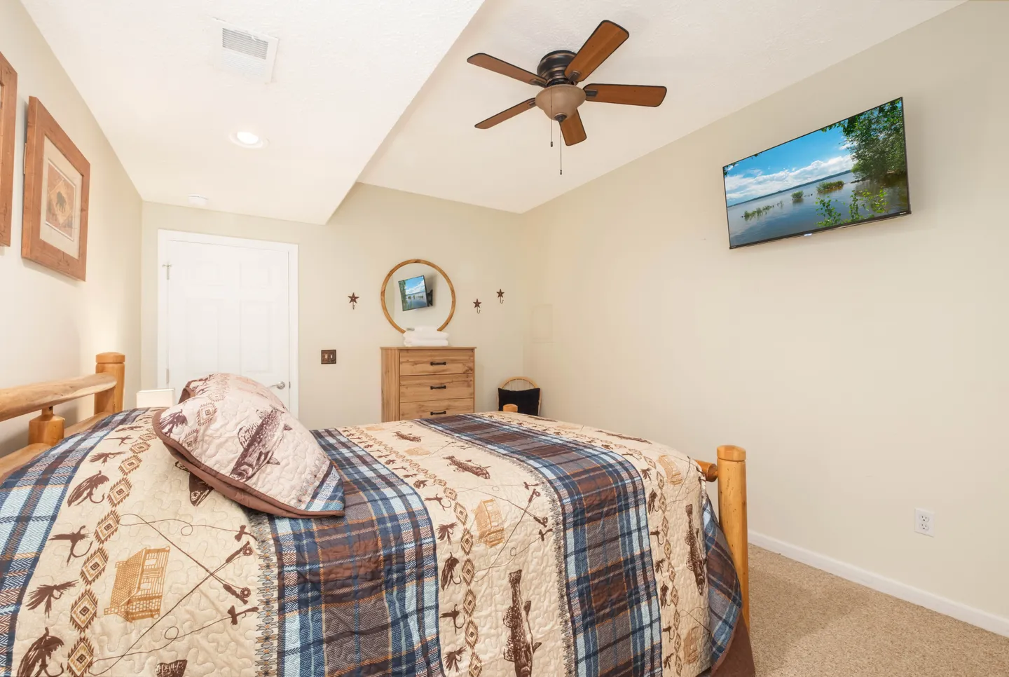 Bedroom with a log bed frame, rustic bedding, a ceiling fan, and a wall-mounted TV.