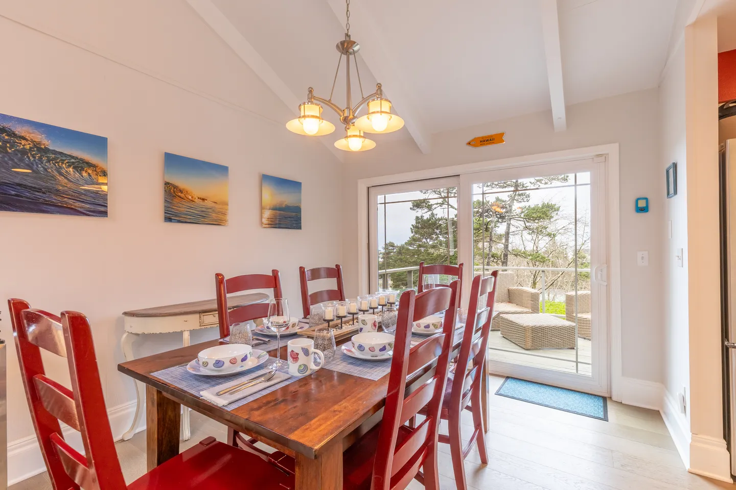 Dining room with a wooden table, red chairs, and sliding glass doors leading to an outdoor deck.
