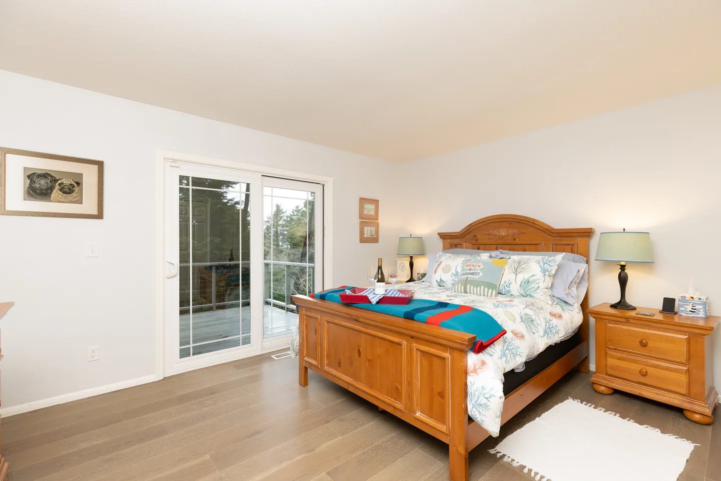 Bedroom with a wooden bed frame, patterned bedding, matching nightstand, and sliding glass door leading to a balcony.