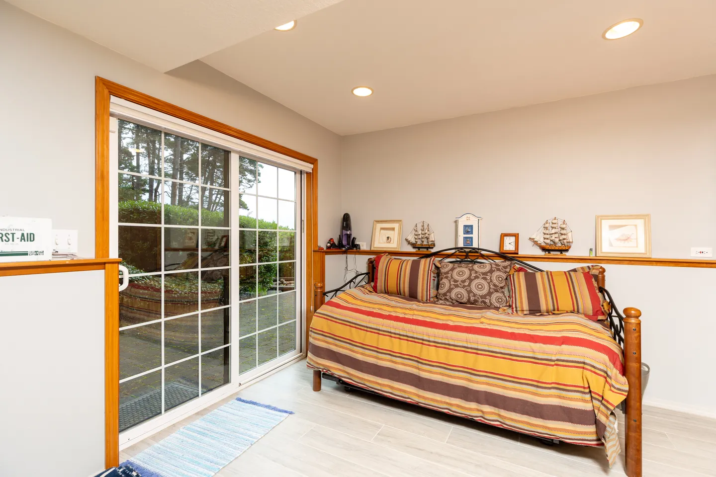 Indoor sitting area or bedroom featuring a daybed with a striped comforter and sliding glass doors leading to an outdoor patio.