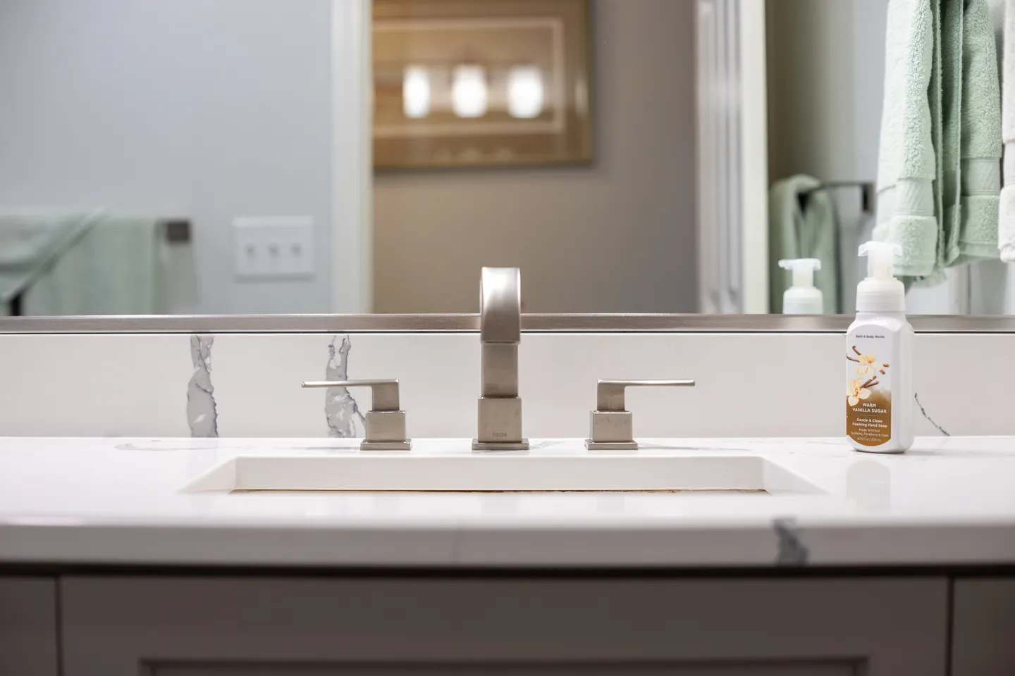 Close-up of a bathroom vanity with an undermount sink, brushed nickel faucet, and marble-look countertop.