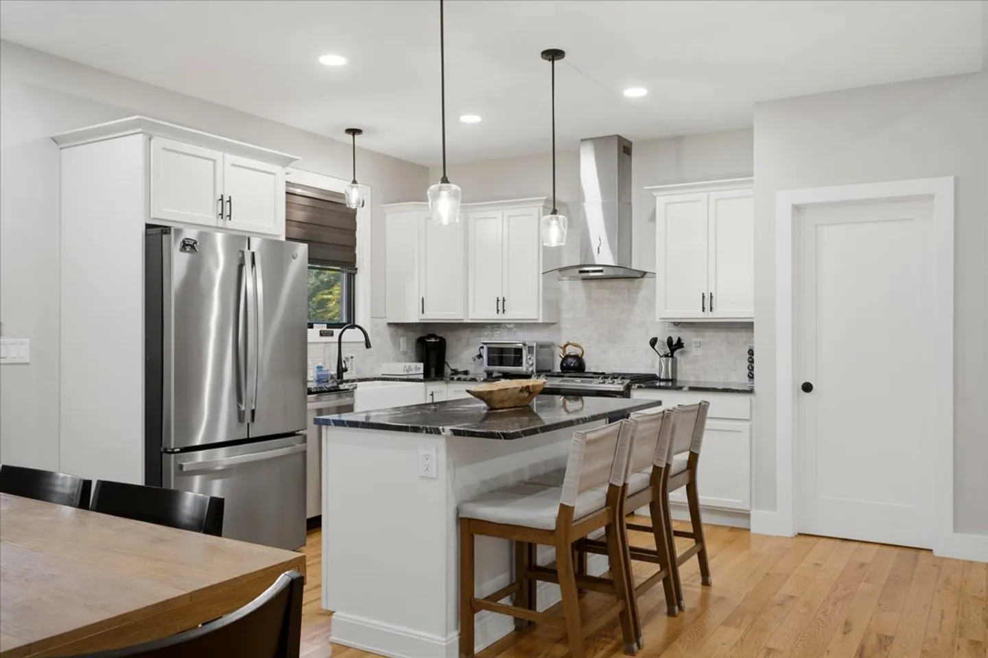 Kitchen with white cabinetry, dark countertops, a central island with bar seating, and stainless steel appliances.