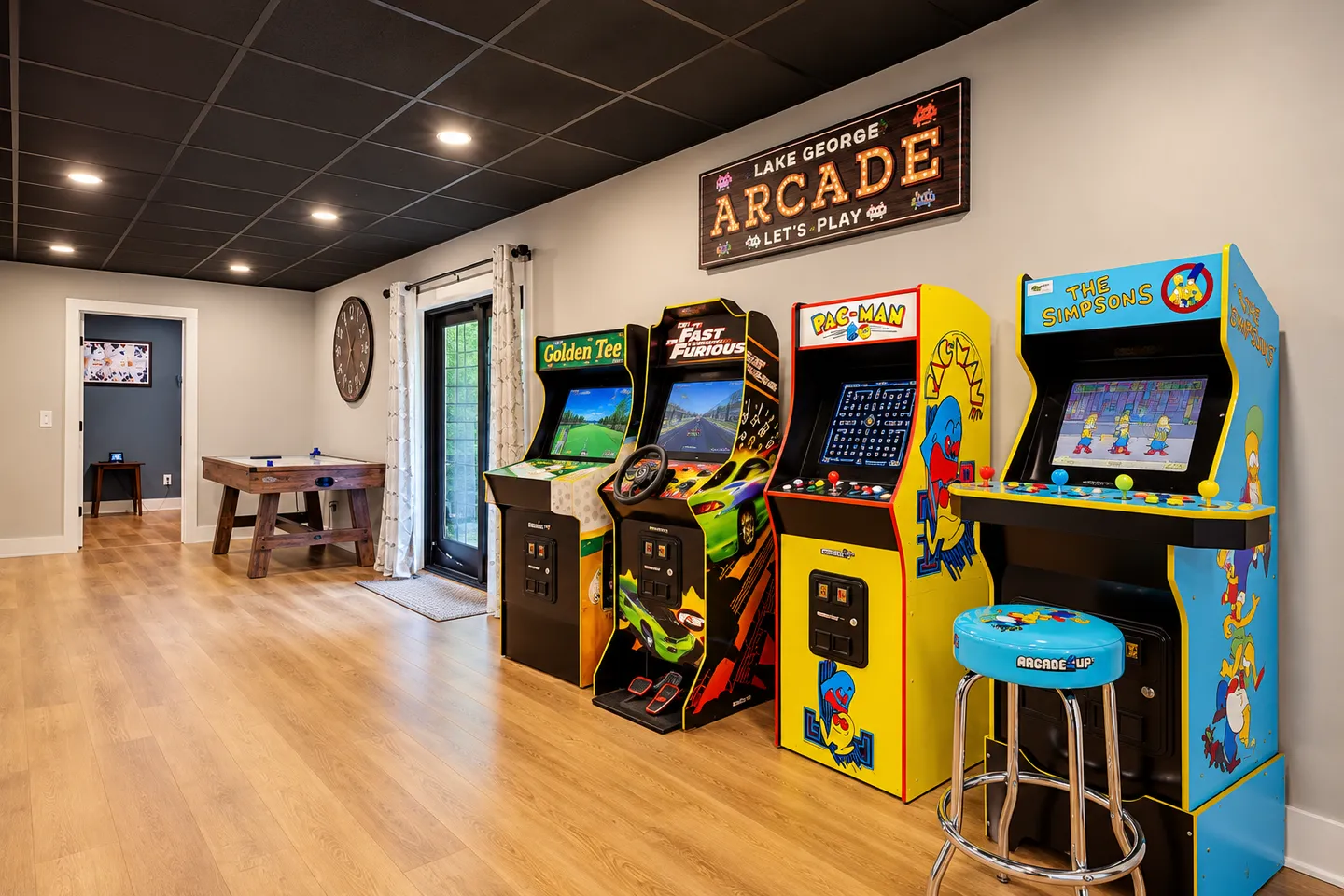 Game room with wood-style flooring, a dark drop ceiling, multiple arcade cabinets, and an air hockey table.