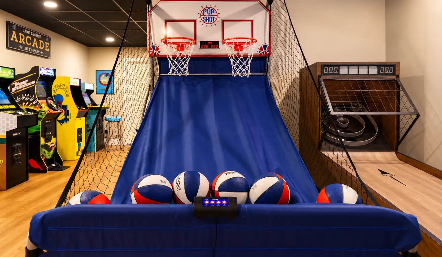 Game room featuring a dual-hoop Pop-A-Shot basketball arcade game, a skeeball machine, and several classic arcade cabinets.