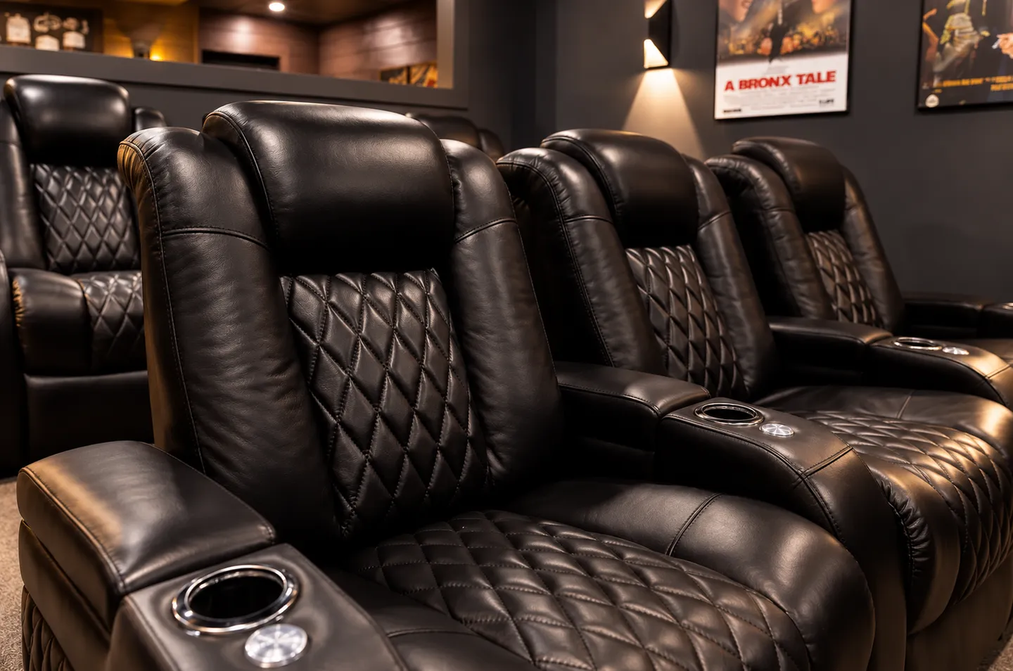 Rows of black leather theater recliners with diamond stitching and cup holders in a home cinema room.