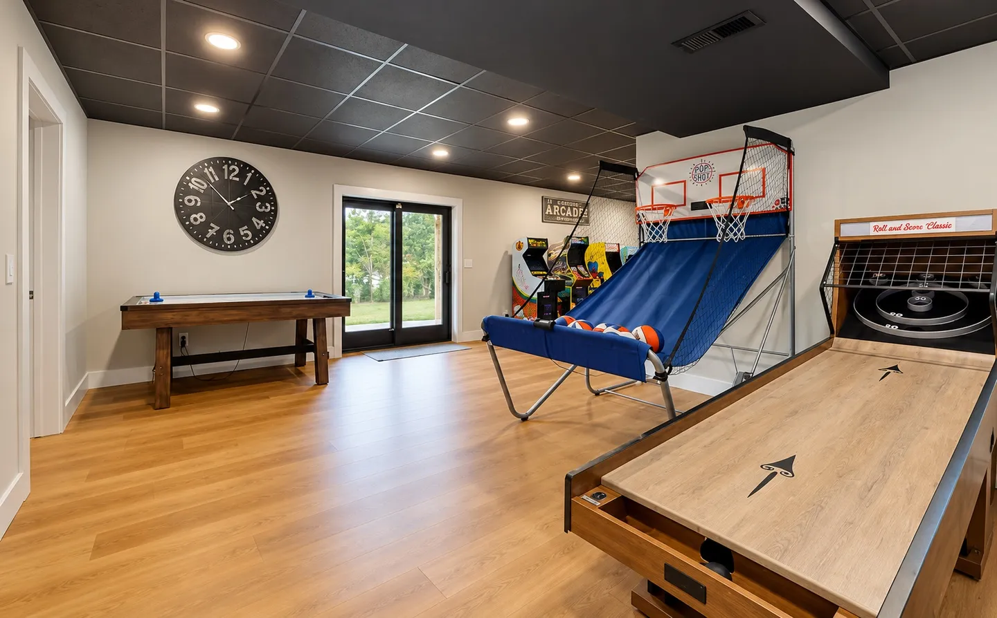 Game room with an air hockey table, basketball shootout game, roll and score classic game, and arcade machines.