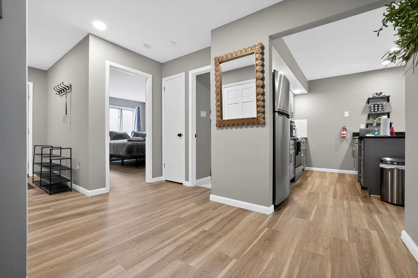 Hallway with wood-look flooring leading to a bedroom on the left and an adjacent kitchen on the right.