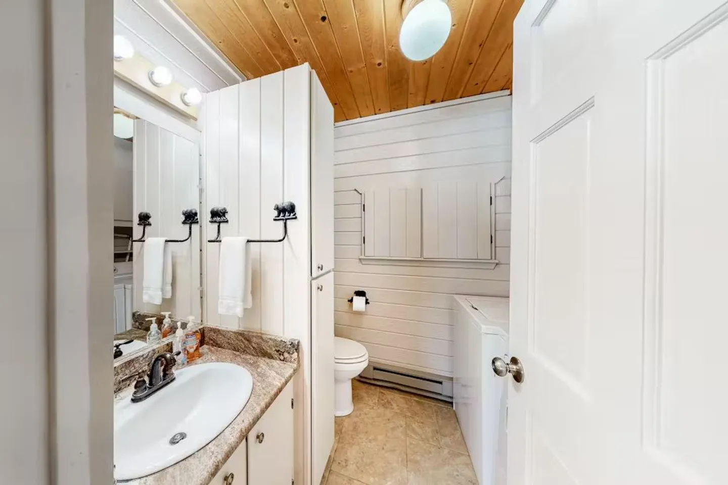 Bathroom with vanity, toilet, laundry machine, white paneled walls, and wood ceiling