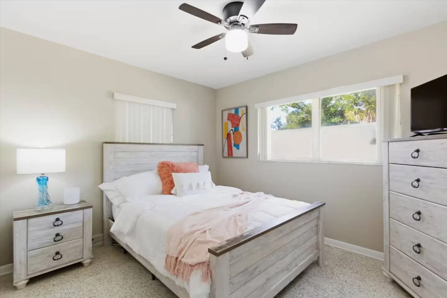 Bedroom with a wooden bed, matching nightstand and dresser, a ceiling fan, and carpet flooring.