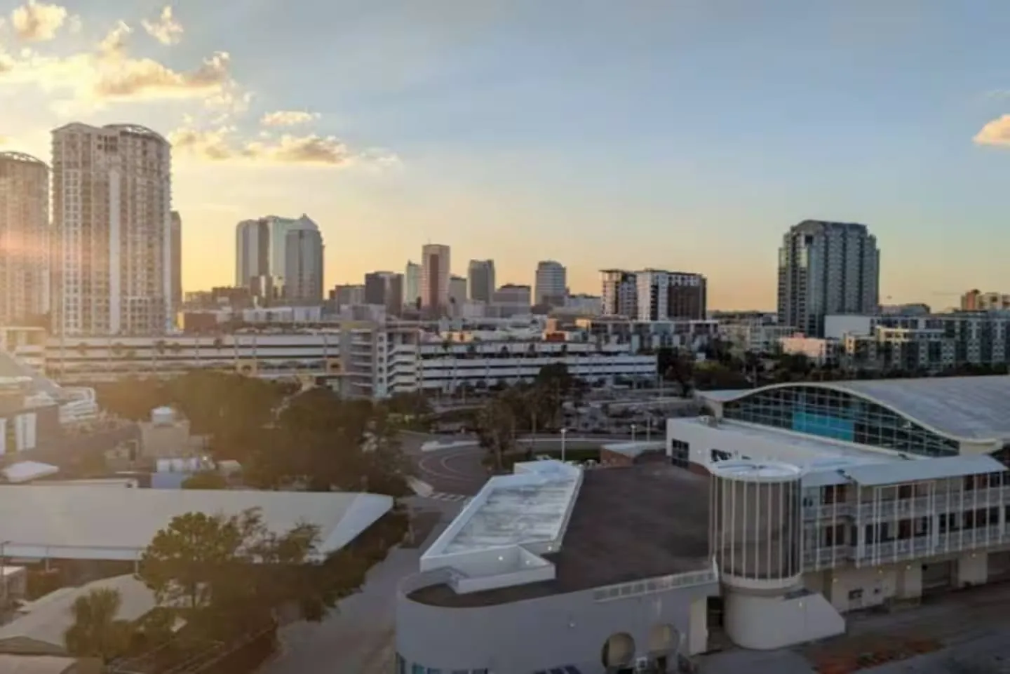 Elevated view of a city skyline with skyscrapers and low-rise buildings under a sunset sky.