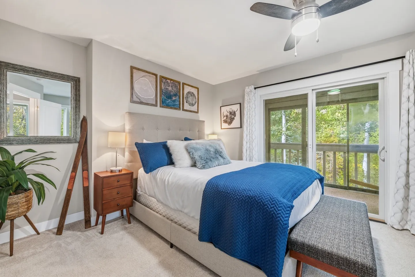 Bedroom with an upholstered bed, blue accents, carpeted flooring, and sliding glass doors leading to a balcony.