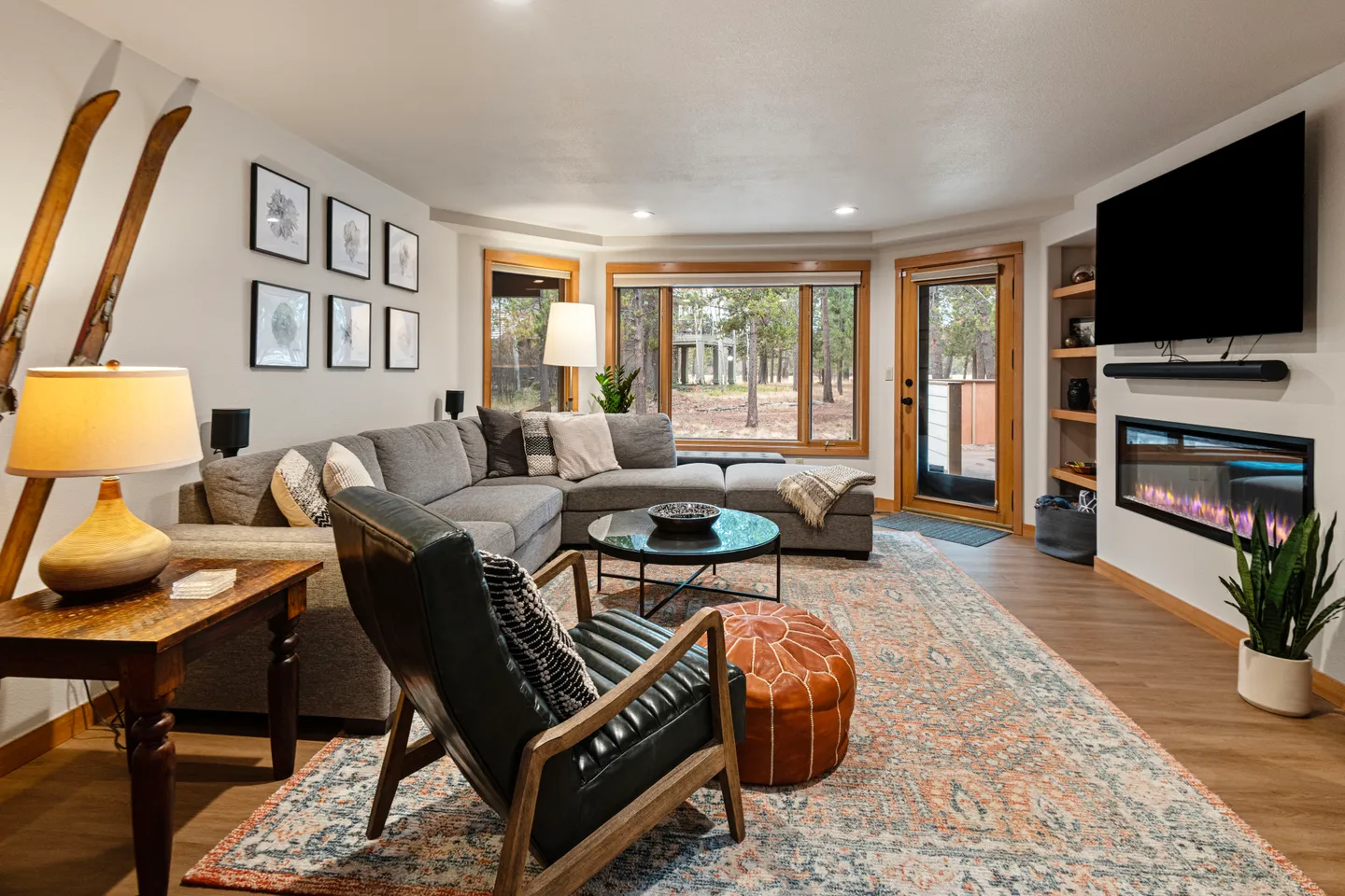 Living room with a sectional sofa, armchair, area rug, wall-mounted electric fireplace, and TV.