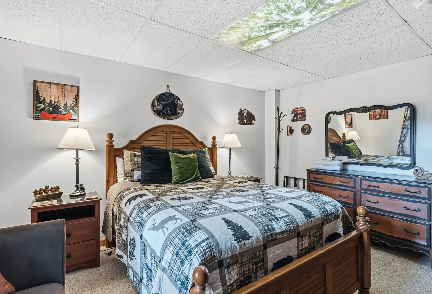 Bedroom with wooden bed, rustic patterned quilt, nightstands with lamps, and a wooden dresser with a mirror.