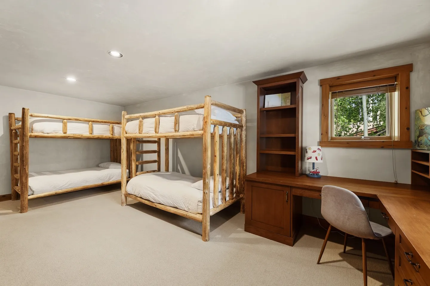 Bedroom with two rustic wooden bunk beds, carpeted floor, and a built-in wooden corner desk.