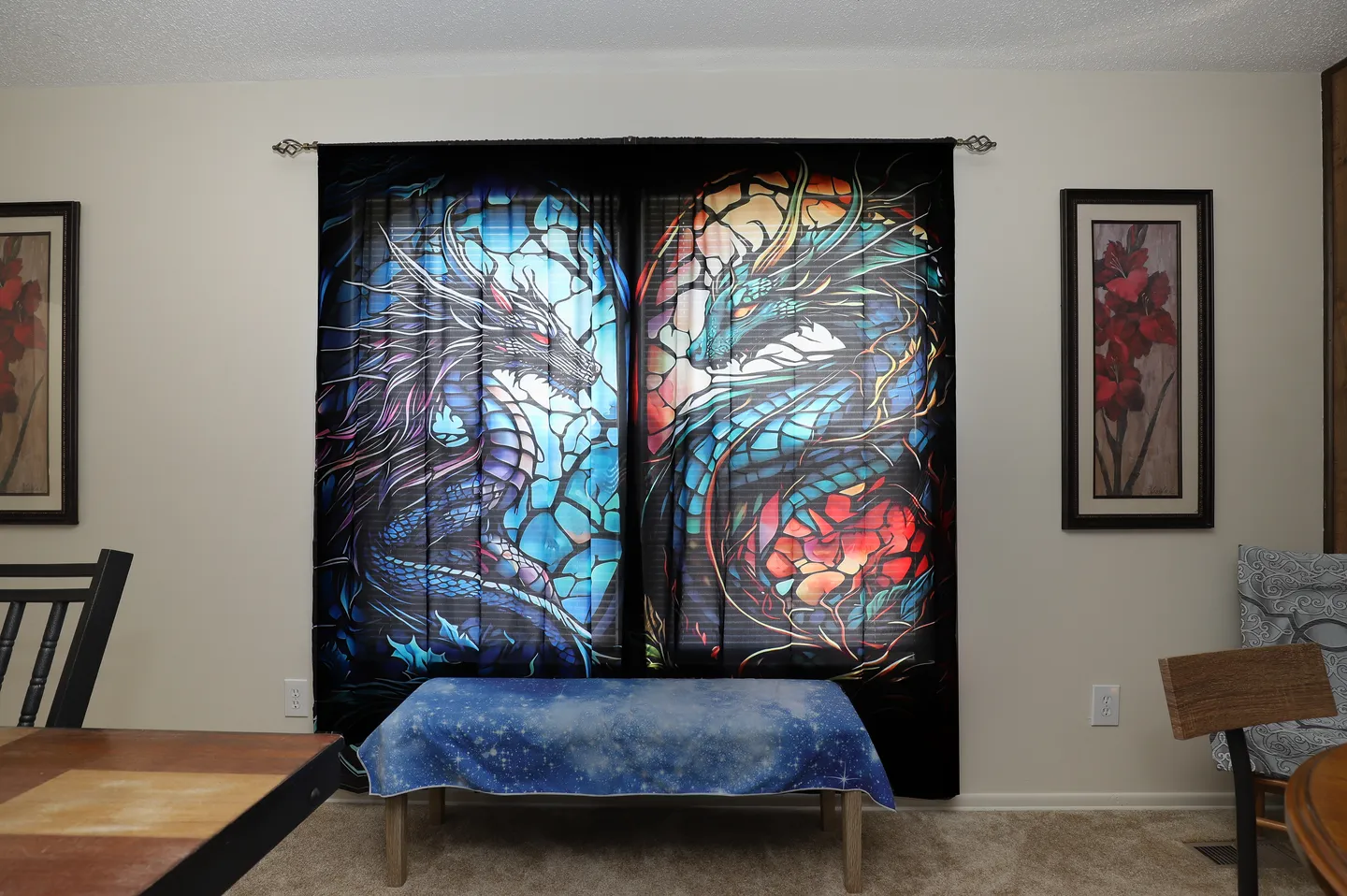 Indoor dining space featuring large graphic curtains depicting dragons flanked by framed art on beige walls.