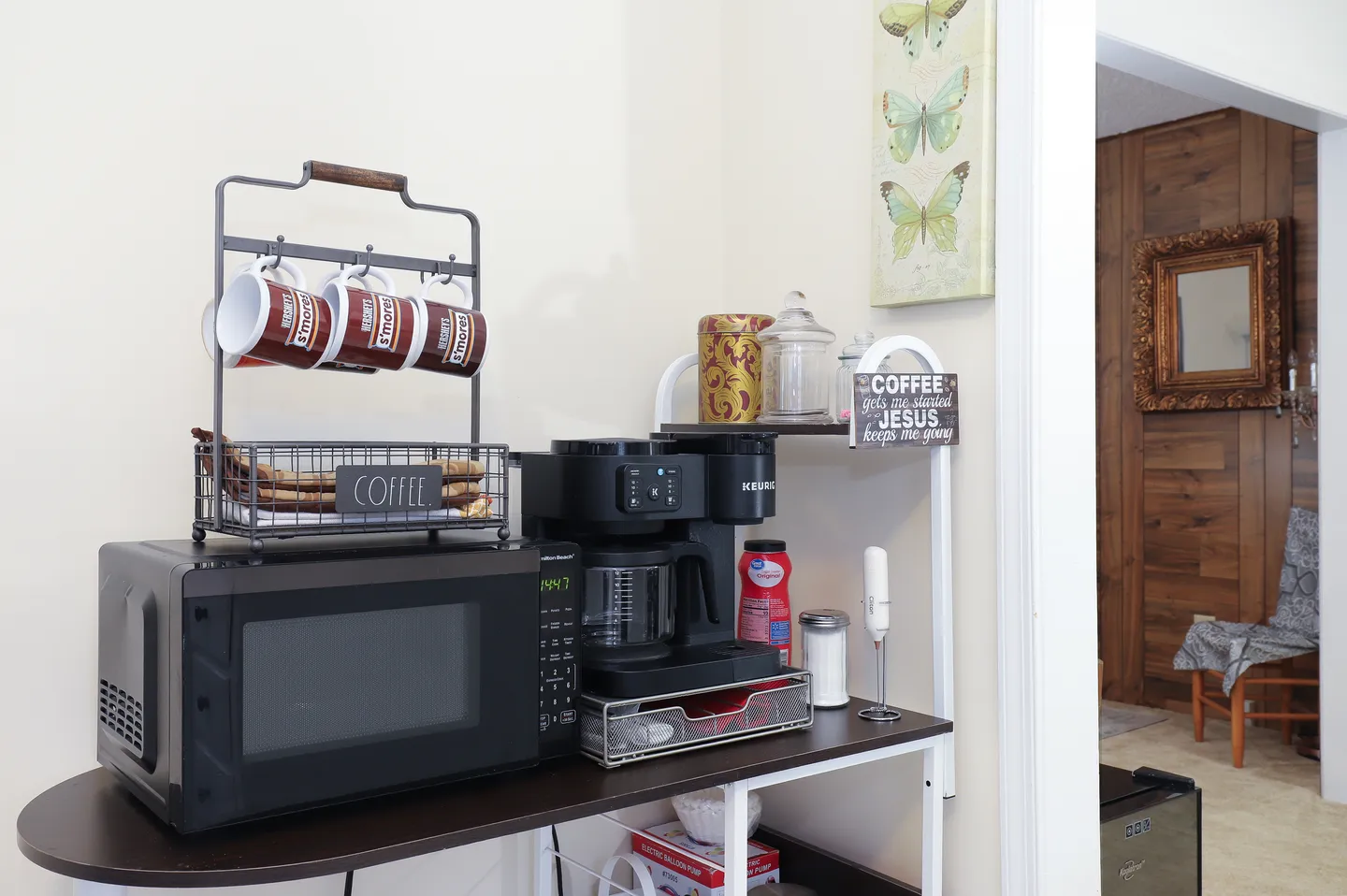 Dedicated coffee station and microwave setup on a small shelving unit next to an open doorway.