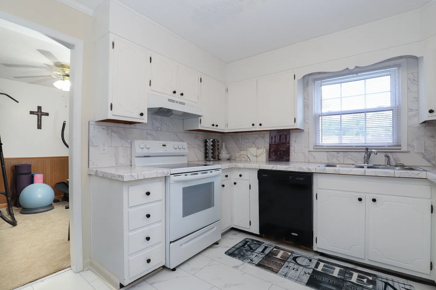 Kitchen with white cabinetry, marble-patterned countertops, a white electric range, and a black dishwasher.