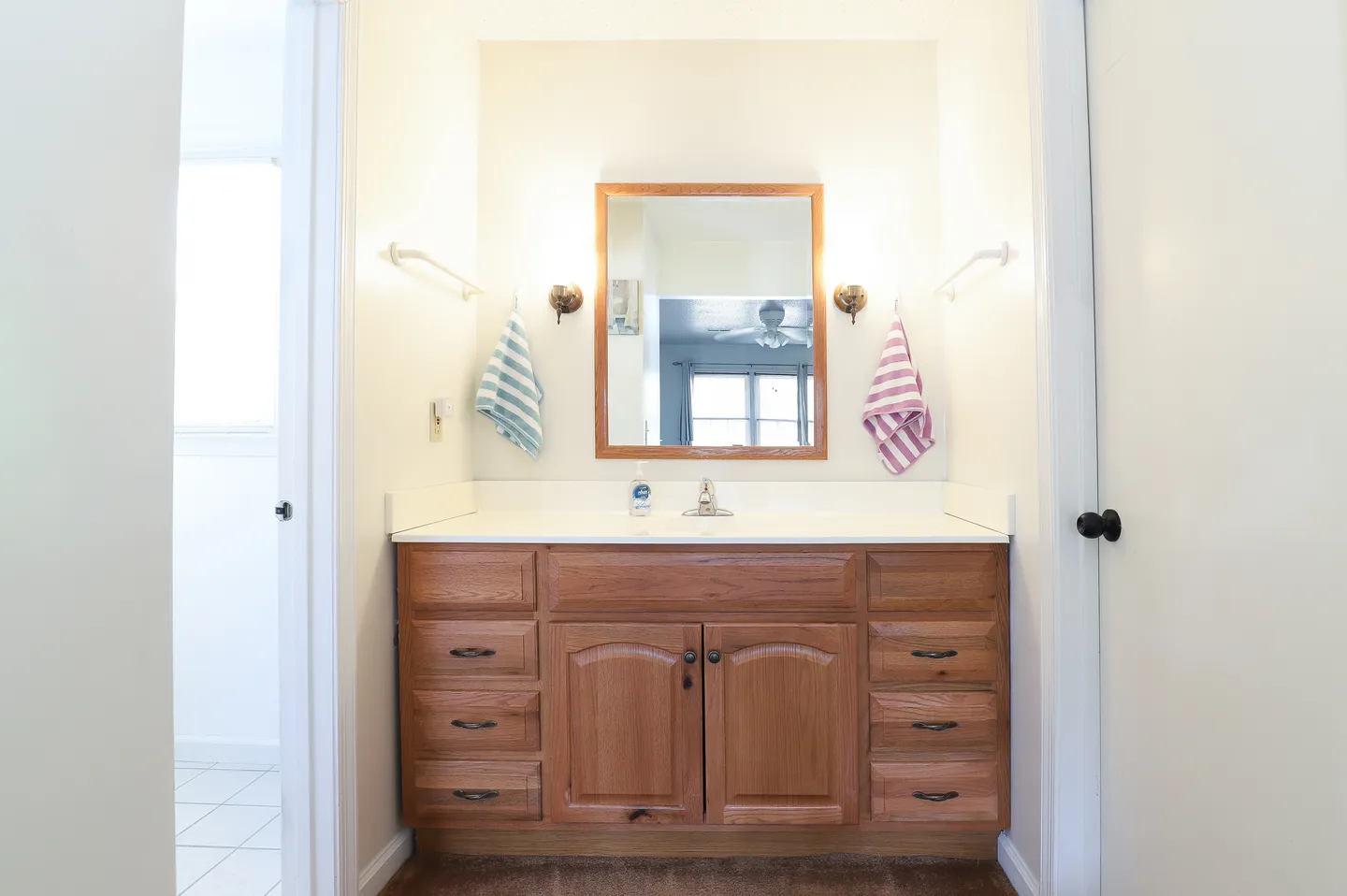 Bathroom vanity area featuring a wooden cabinet with multiple drawers, a mirror with a wood frame, and dual wall sconces.