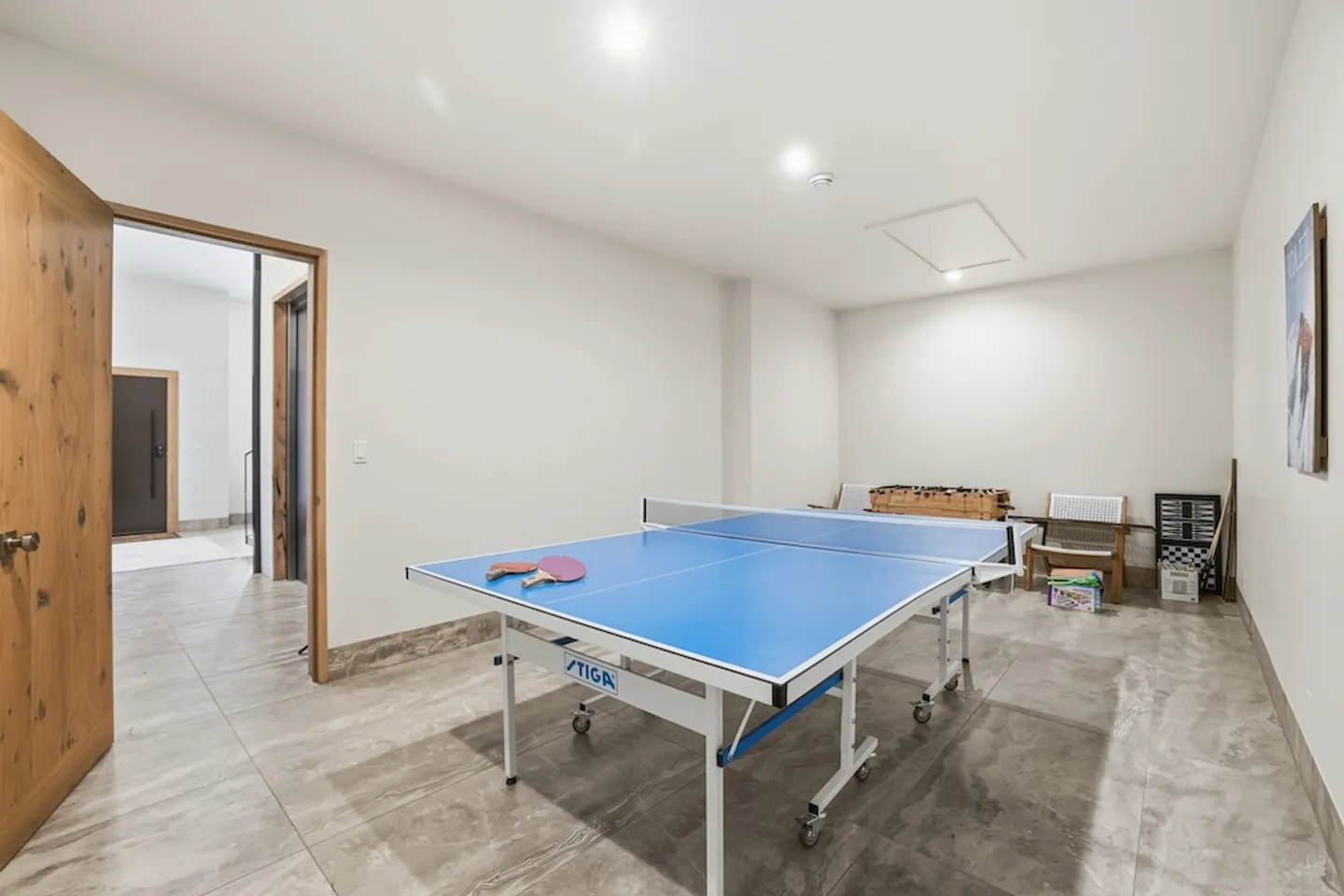 Game room featuring a blue ping pong table in the center, tiled floors, and white walls.