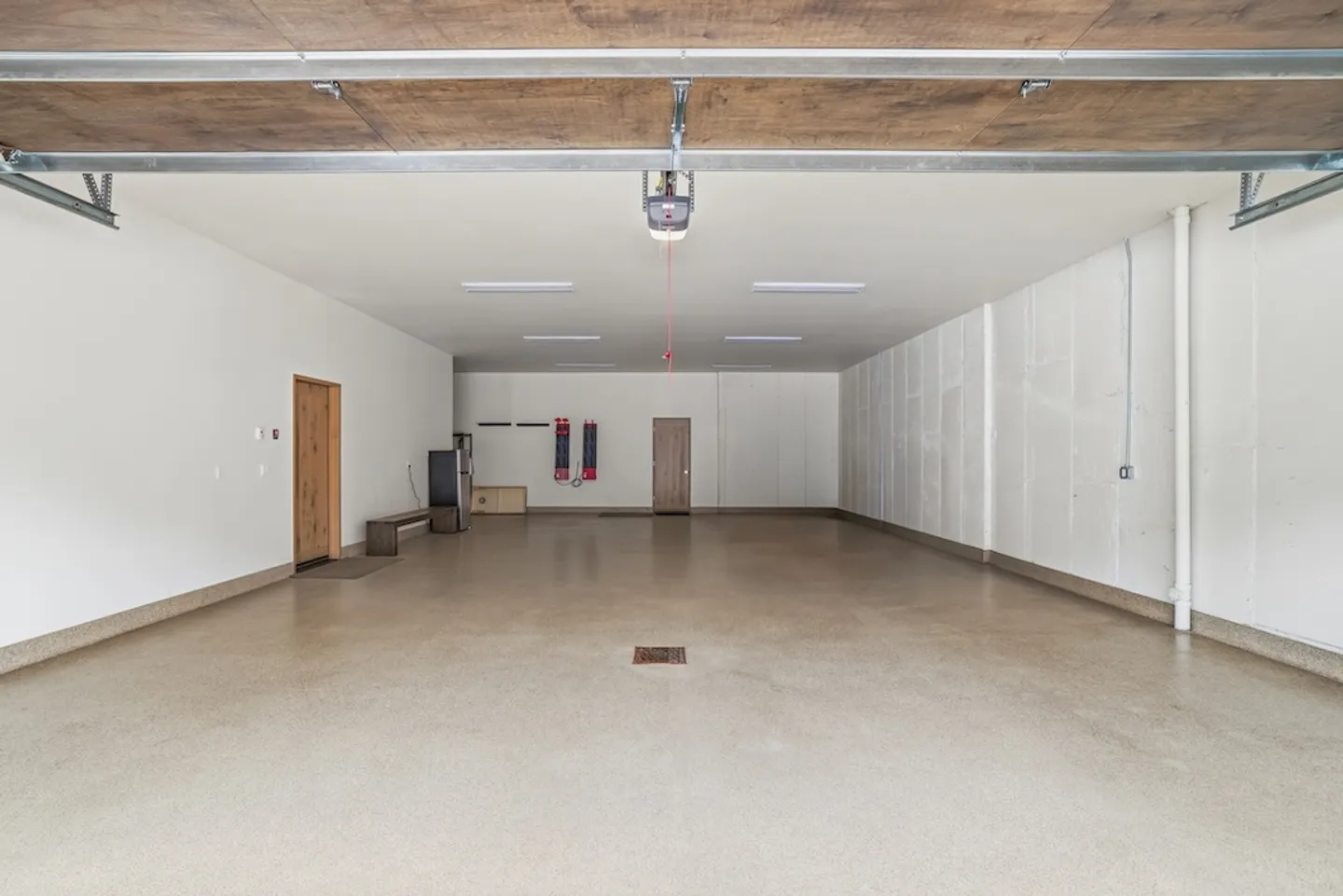 A spacious, empty garage with clean epoxy-style floors, white walls, and overhead lighting.