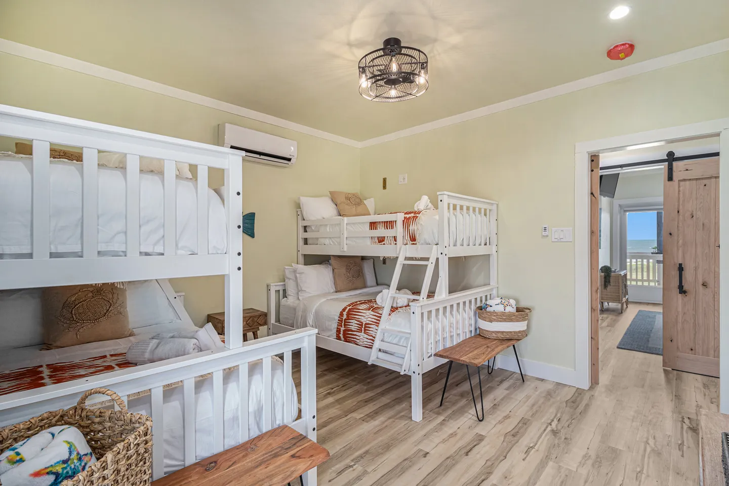 Bunk bedroom with two sets of white wooden bunk beds and wood-look flooring.