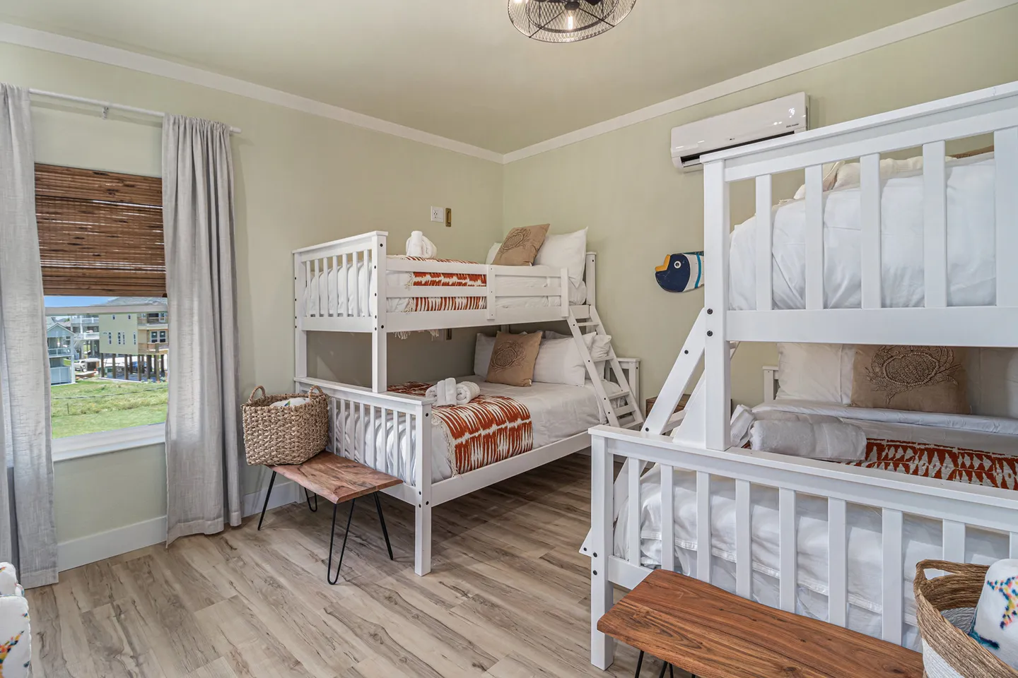 Bedroom featuring two white bunk bed sets with patterned bedding, wood-look flooring, and a window.