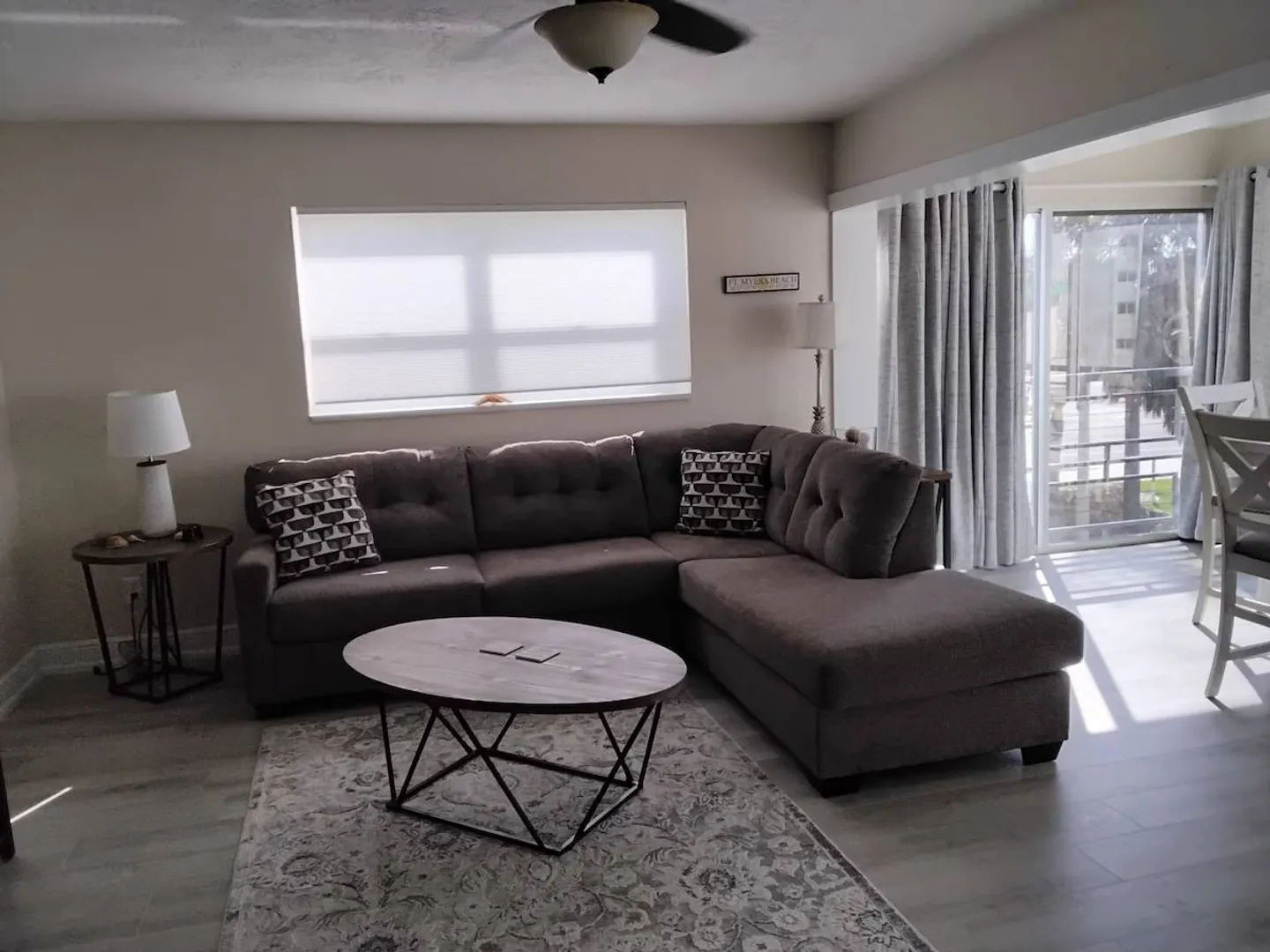 Living room featuring a grey sectional sofa, coffee table, area rug, and sliding glass doors leading outside.