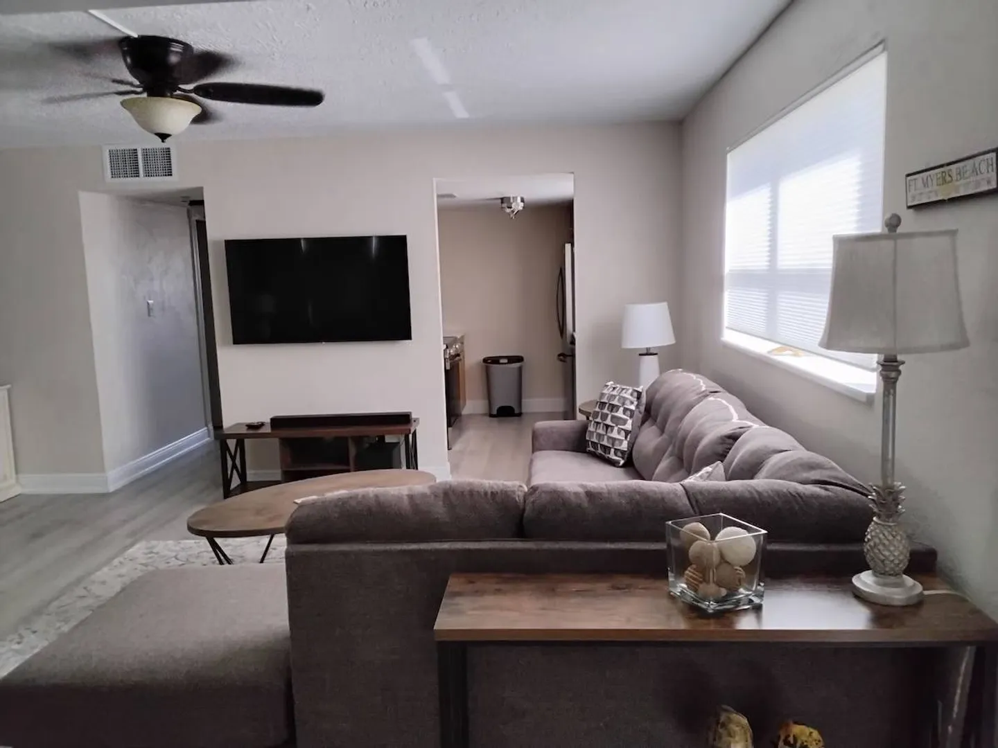 Living room featuring a large sectional sofa, wall-mounted television, coffee table, and ceiling fan.