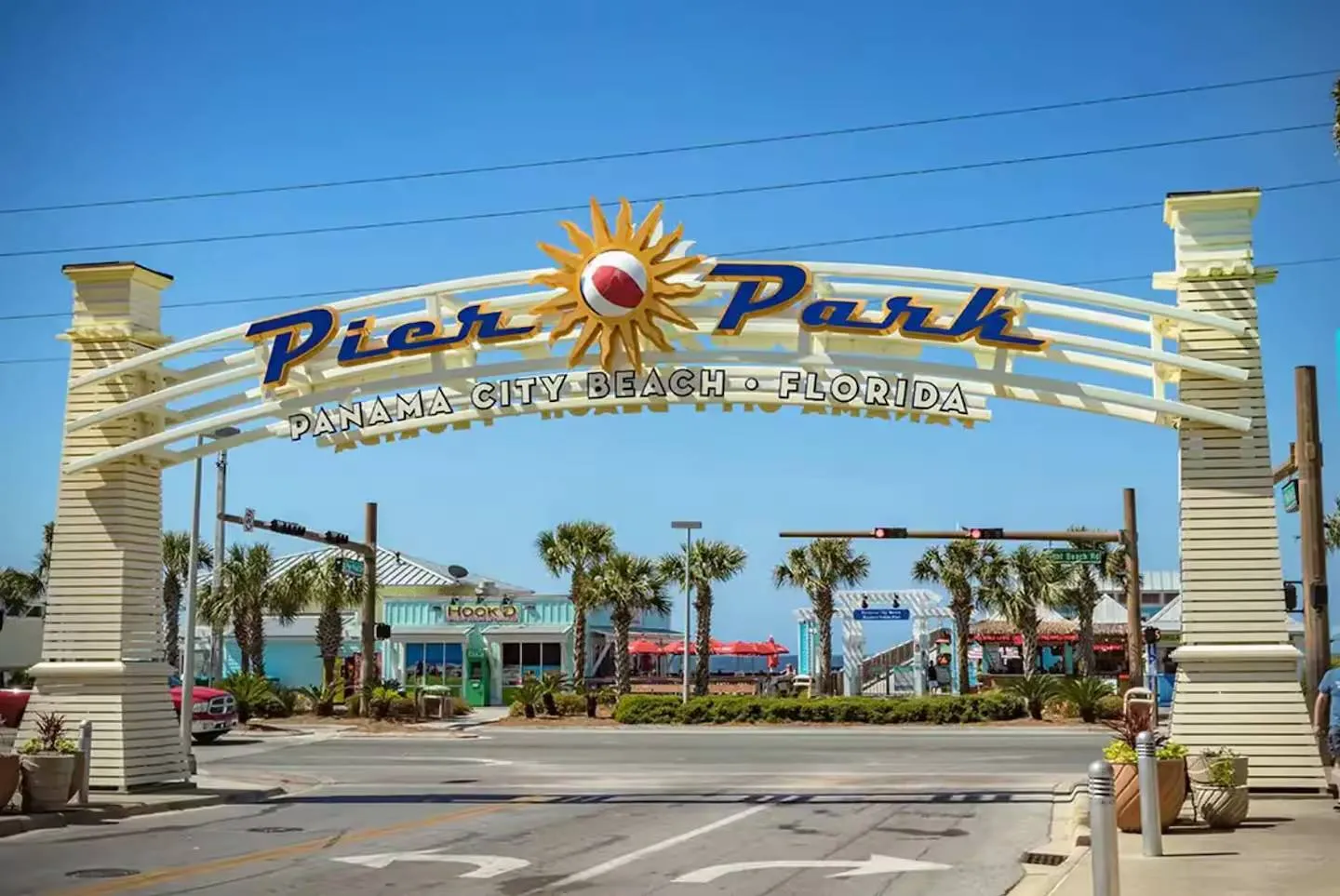 Pier Park entrance archway in Panama City Beach, Florida, framing palm trees and coastal shops under a clear blue sky.