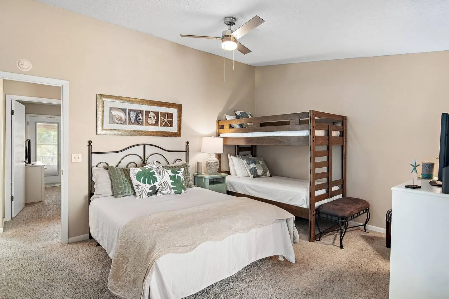 Bedroom with carpet flooring, a bed with a dark metal frame, a wooden bunk bed, and a ceiling fan.