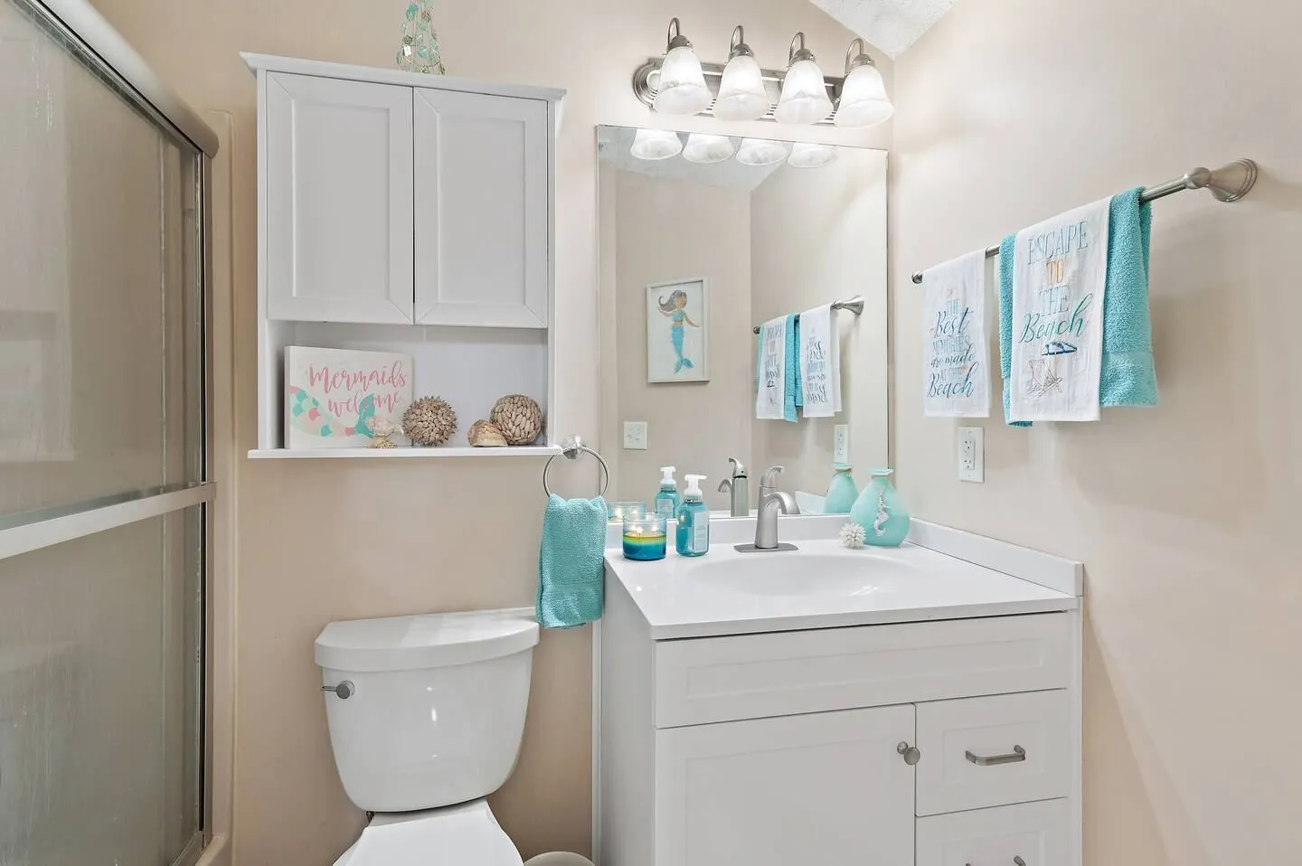 Bathroom featuring a white vanity with mirror and lighting, toilet, wall cabinet, and sliding glass shower door.