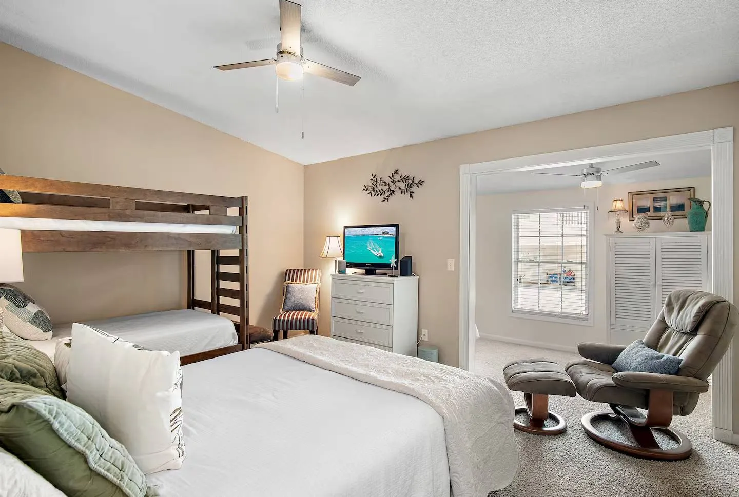 Bedroom featuring a primary bed, wooden bunk beds, a television on a dresser, and an open doorway leading to an adjoining room.